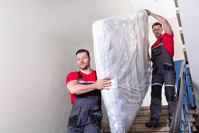 two workers lifting a box spring out of a bedroom in Rogue River, OR